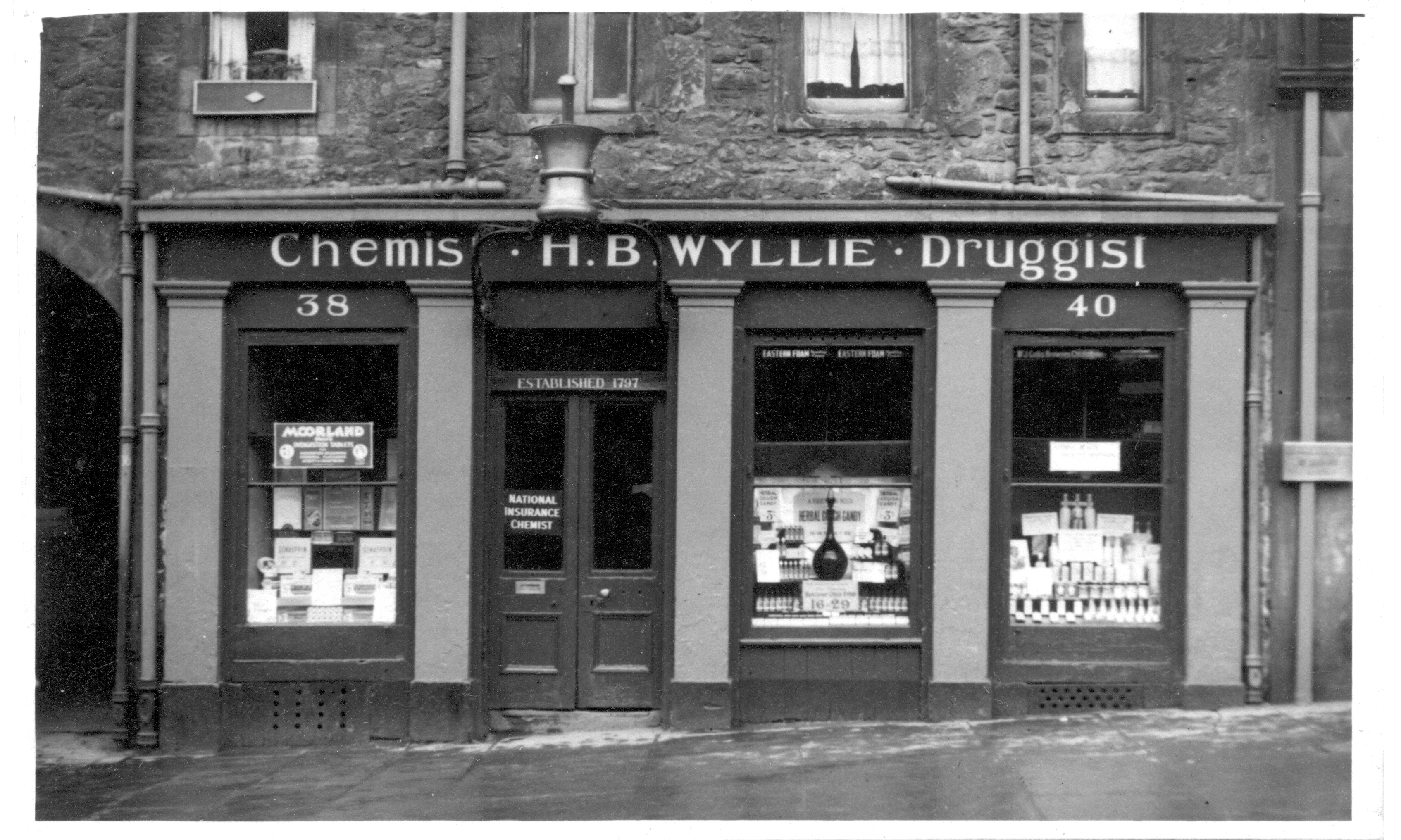 LDRPS: SZ3086, 1953. This black and white photograph shows the exterior of H.B Wyllie, a chemist and druggist in Edinburgh. The business was established in 1797 LDRPS: SZ3086, 1953. This black and white photograph shows the exterior of H.B Wyllie, a chemist and druggist in Edinburgh. The business was established in 1797